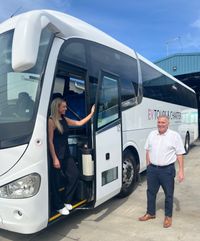 Elyce standing on the step of a bus smiling at her dad.