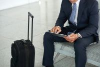 A business man in a suit sitting in the airport with luggage.