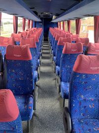 The blue seats of a bus loking down the aisle.
