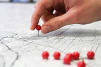 Closeup of a hand putting pins in a map