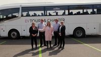 The EV Tours and Charter team standing together in front of a bus