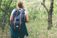 School girl walking through the trees with a backpack