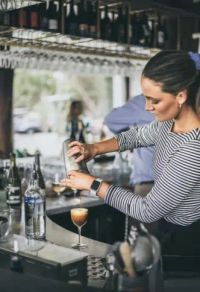 John sitting in the drivers seat of a bus with Elyce sititng behind him